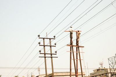 Low angle view of electricity pylon against clear sky