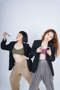 Portrait of lesbian couple holding pen standing against gray background