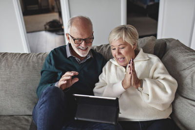 Man and woman using mobile phone while sitting on sofa