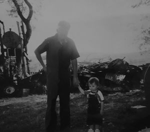 Boy standing by tree against sky