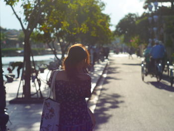 Rear view of woman walking on road in city