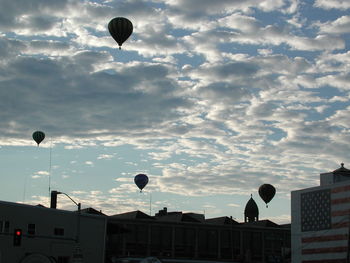 Hot air balloons flying in city against sky