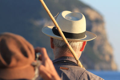 Rear view of man holding hat