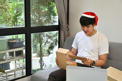 Man looking at camera while sitting on window at home