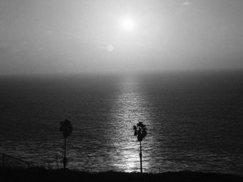 Silhouette people in sea against sky