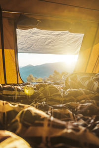 View through camping tent with warm blanket on hills at dawn in early morning during relaxing hiking trip