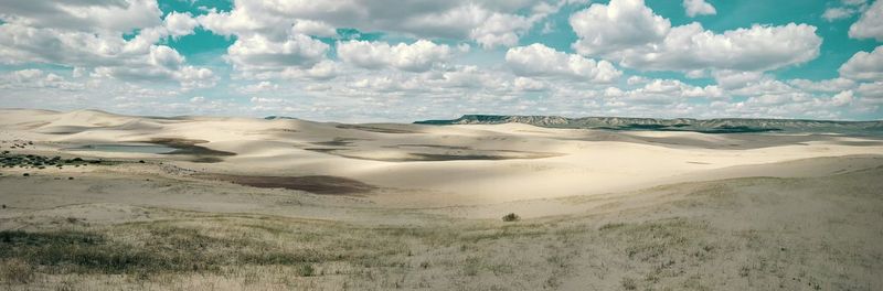 Panoramic view of sand dunes against sky