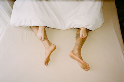 Low section of woman standing on bed at home