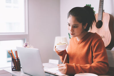 Young woman using mobile phone while sitting on table