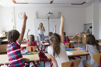 Active pupils raising their hands in class