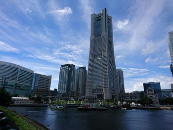 Modern buildings by river against sky in city