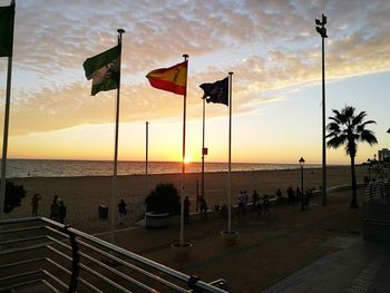 Scenic view of flag by sea against sky during sunset