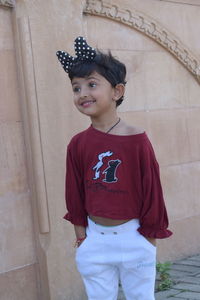 Portrait of smiling boy standing against wall