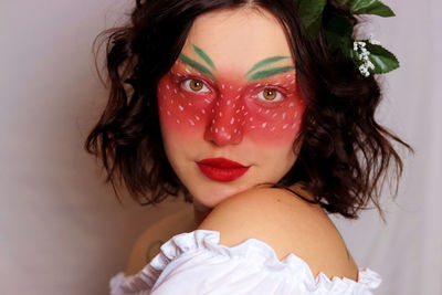 Close-up of young woman with face paint against wall