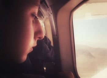 Close-up of boy holding airplane window