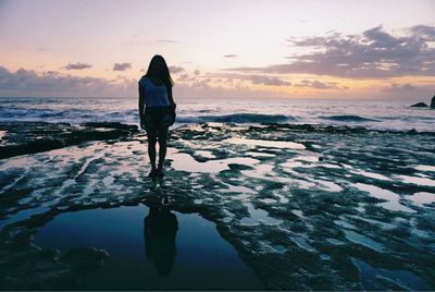 Woman standing on beach at sunset