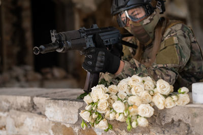 Caucasian woman in army uniform holding a machine gun.