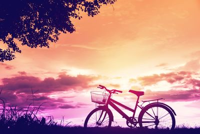 Silhouette bicycle on field against sky during sunset