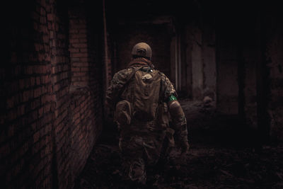 Rear view of soldier walking by wall at night