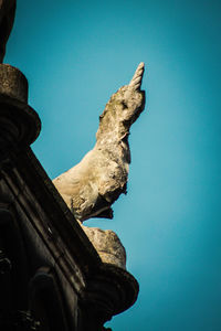Low angle view of animal statue against clear blue sky