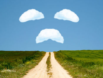 Road amidst field against sky