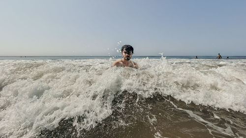 Rear view of woman standing in sea against sky