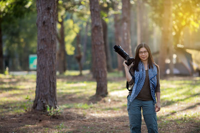 Portrait of woman holding camera in forest