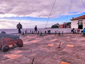 People sitting on street against sky in city