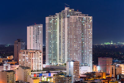 Modern buildings in city against sky at night