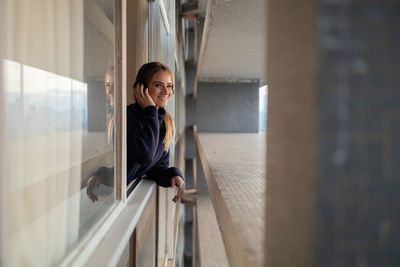 Portrait of young woman looking through window