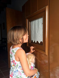 Woman looking through window at home