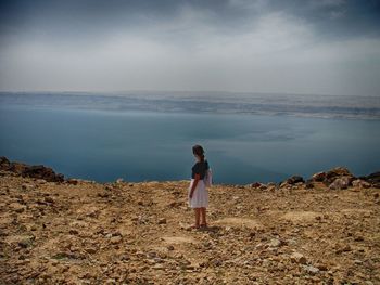 Rear view of man standing on sea shore against sky