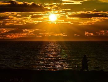 Silhouette woman on beach against sky during sunset