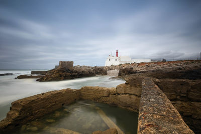 Lighthouse by sea against sky