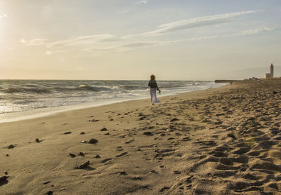 Rear view of woman on beach against sky