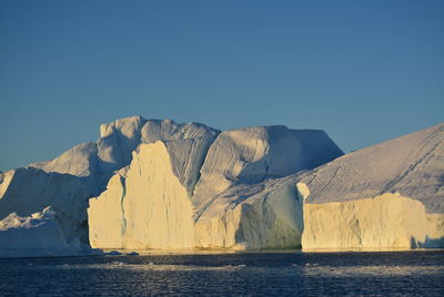 Scenic view of sea against clear sky with beautiful icebergs in the midnight sun ilulissat greenland