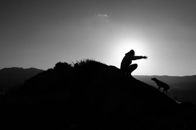 Silhouette man with dog during sunset