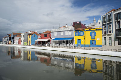 Residential buildings by canal against sky in city