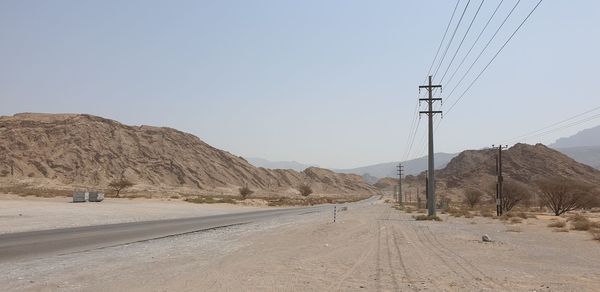 Road leading towards mountains against clear sky