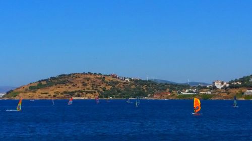 Sailboats in sea against clear blue sky