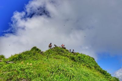 Low angle view of people on mountain against sky