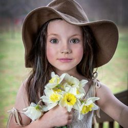 Close-up portrait of a girl holding red flowering plant