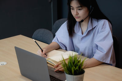 Midsection of woman using mobile phone while sitting on table