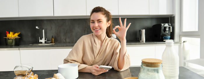 Portrait of young woman drinking coffee in kitchen