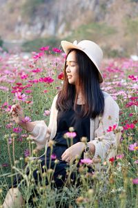 Portrait of young woman looking away while standing by flowers
