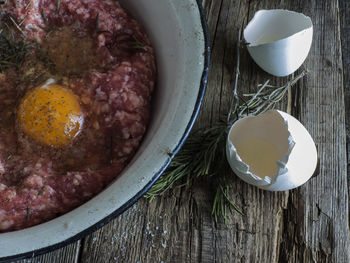 High angle view of minced meat and egg yolk in bowl at table