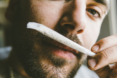 Close-up portrait of bearded man smelling marijuana joint