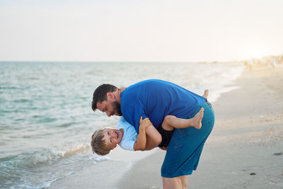 Father with daughter on beach against sky