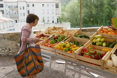 Side view of woman buying vegetables in market