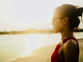 Young woman standing at beach against sky